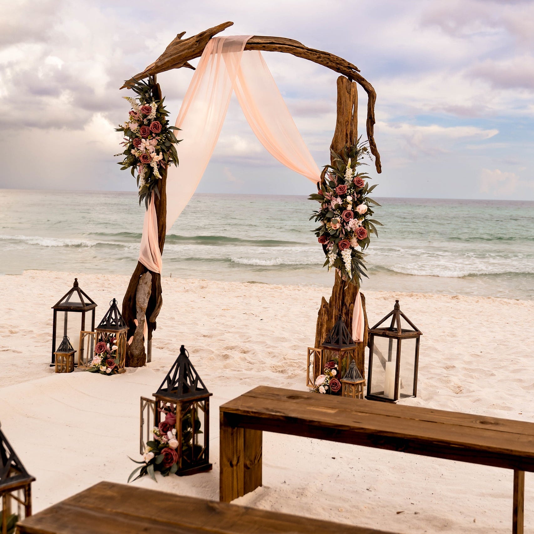 Brown wood bench rentals with driftwood wedding arbor rental in Panama City Beach with custom artificial flower rentals from The Wedding Shop