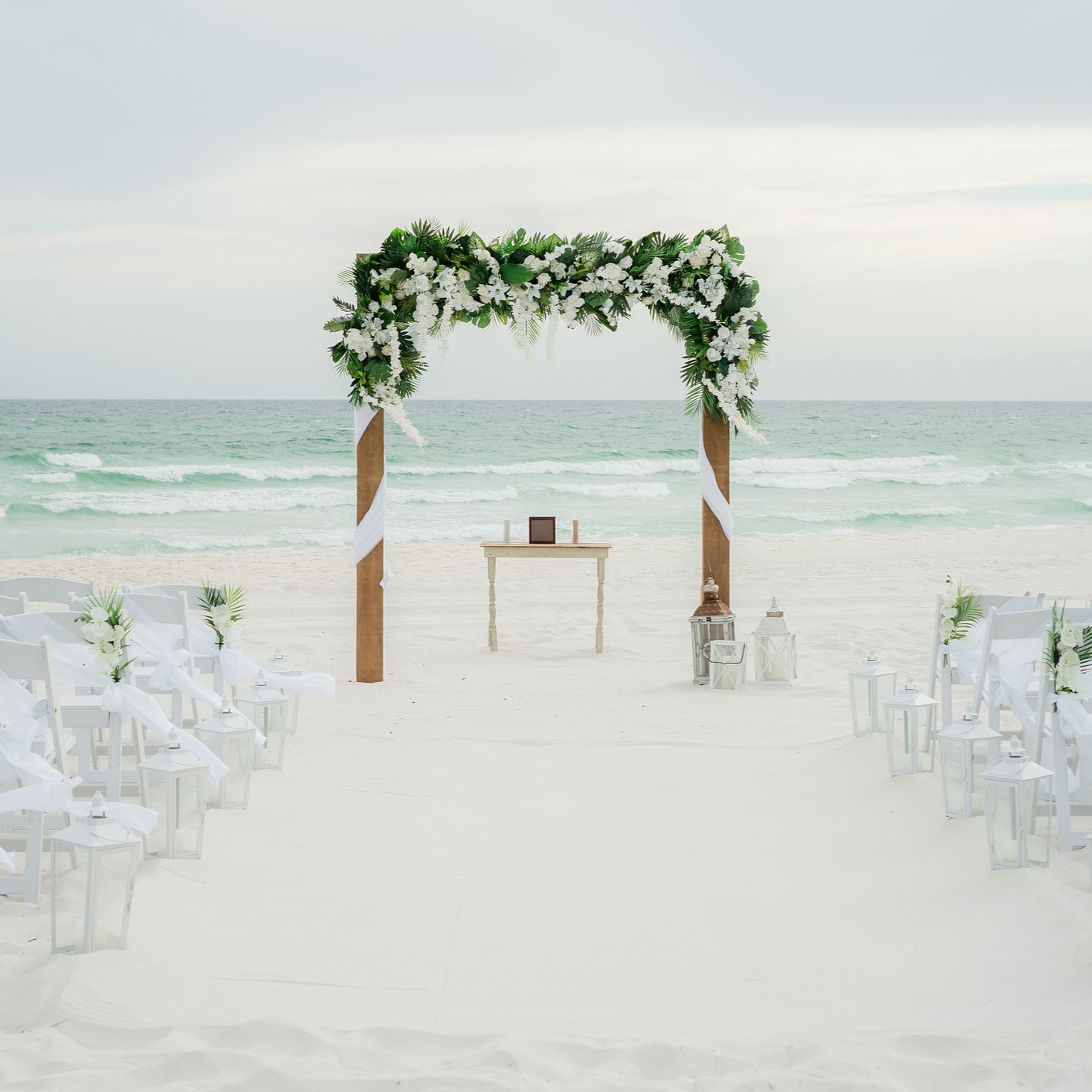 Beach wedding setup with a decorated arch and chairs facing the ocean.