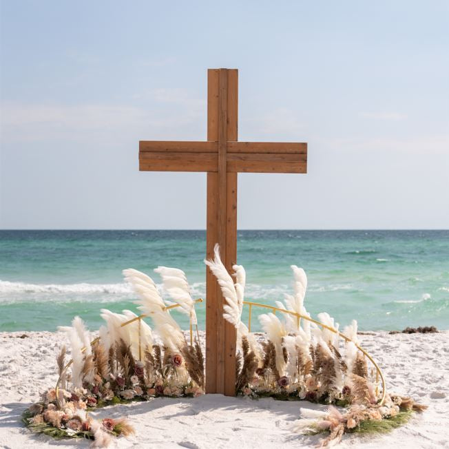 Wooden wedding cross on a sandy beach with ocean in the background