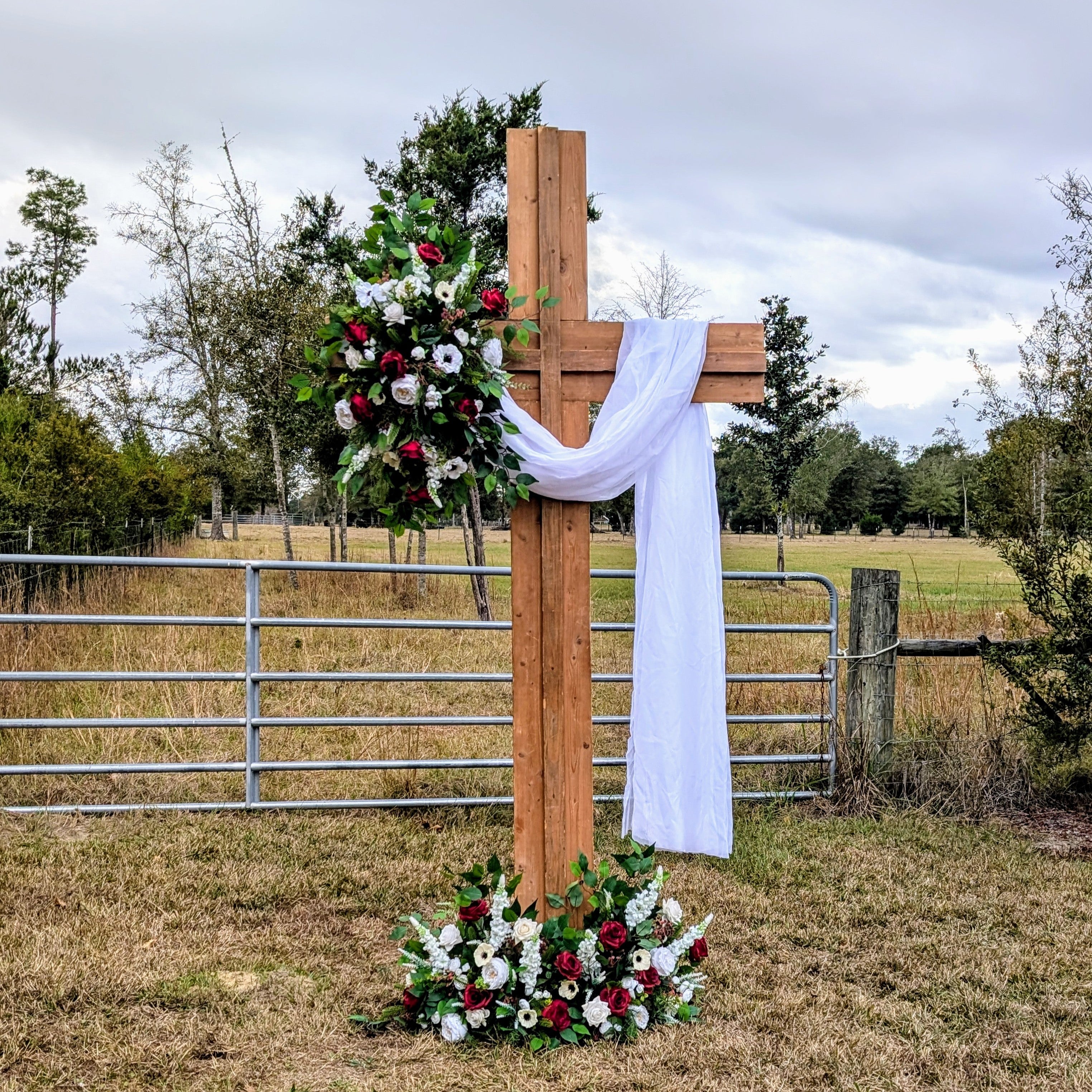 Wooden cross with floral arrangements in a field