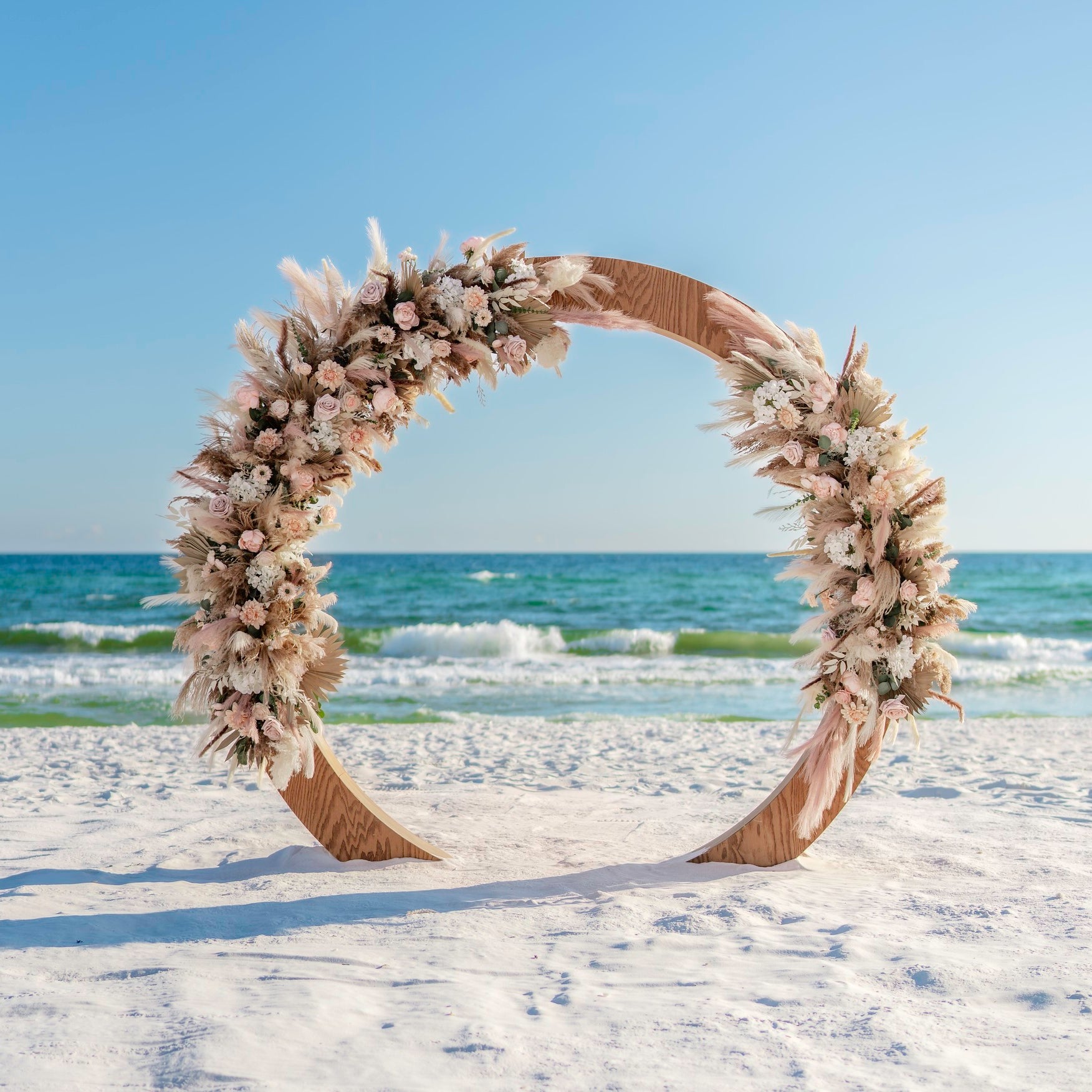 wood circle moon gate wedding arbor rental with boho flowers and pampas grass accents on the beach in panama city beach