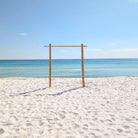Bamboo wedding arch rental in Panama City beach on the sandy beach with clear blue sky and ocean.