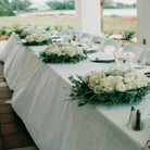 Decorated outdoor wedding table with white flowers and greenery.