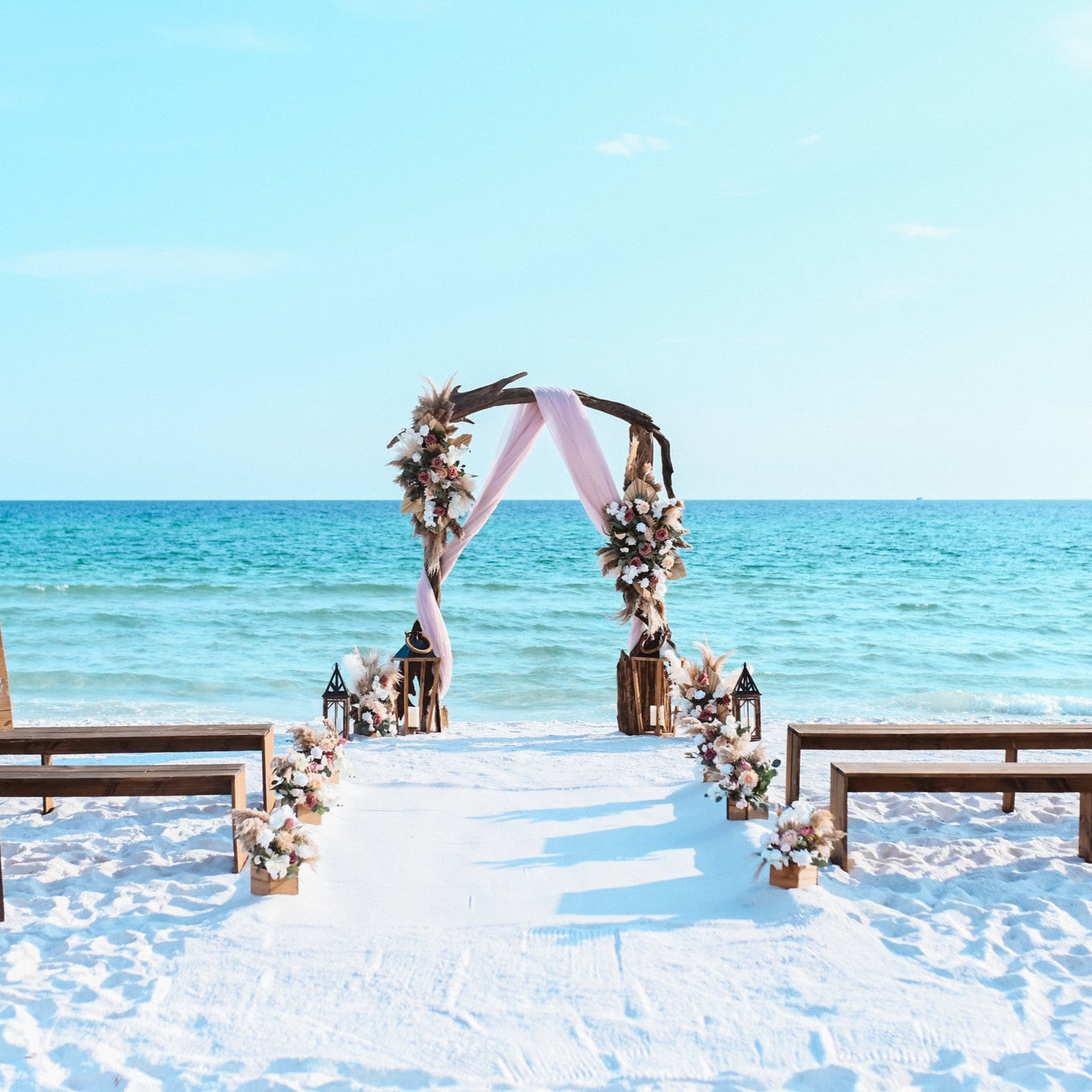 Brown wood bench rentals with driftwood wedding arbor arch and custom artificial wedding flower rentals from The Wedding Shop in Panama City Beach Florida for a destination beach wedding.