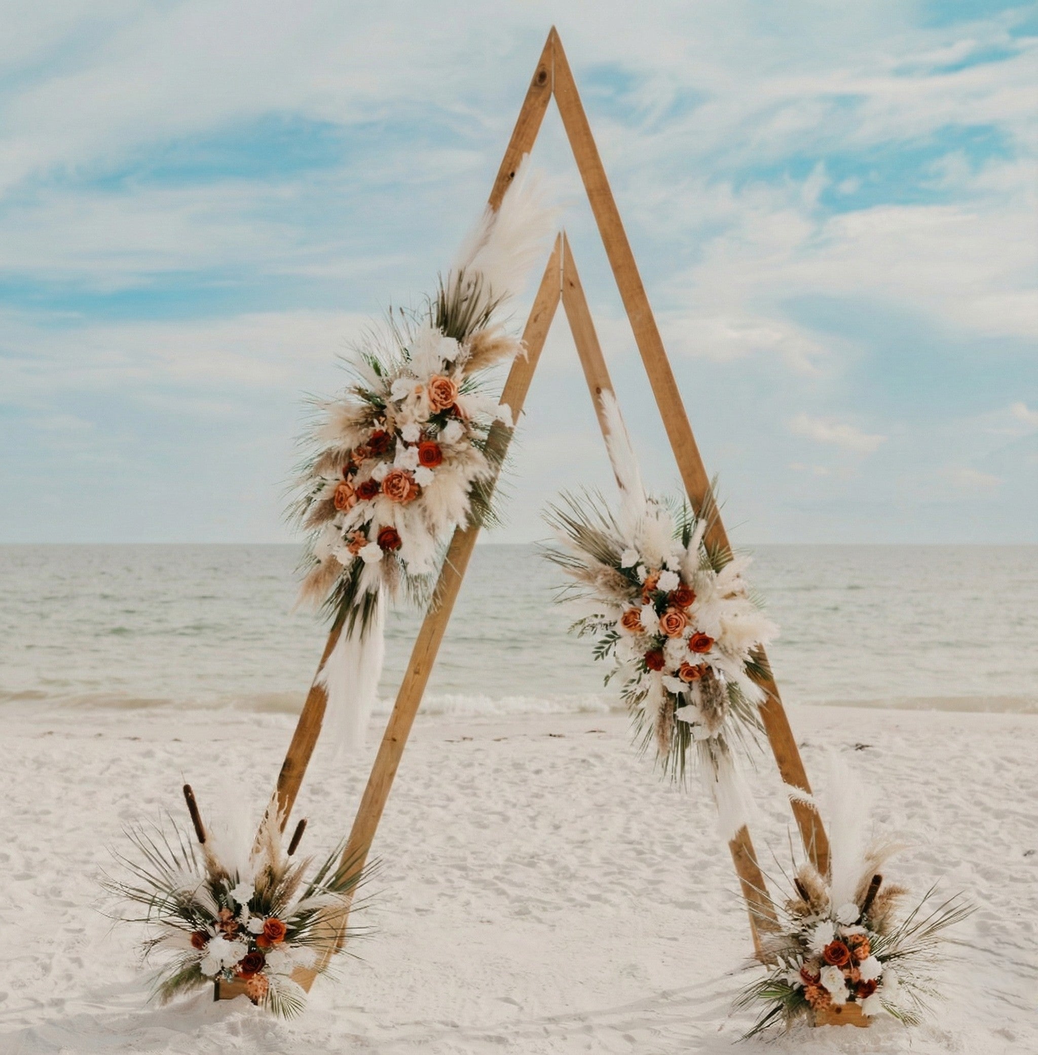 Triangular wooden arch decorated with flowers on a beach