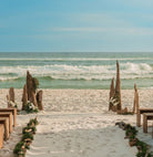 Beach wedding setup with driftwood wedding alter and floral arrangements, ocean waves in the background