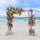 Decorative wedding arch rental with flowers and pampas grass on a sandy beach with ocean view in panama city beach