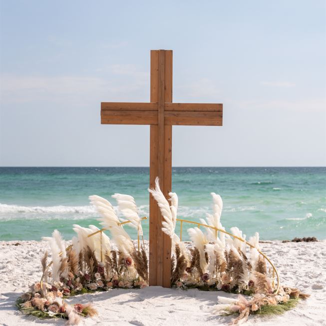 Wooden wedding cross on a sandy beach with ocean in the background