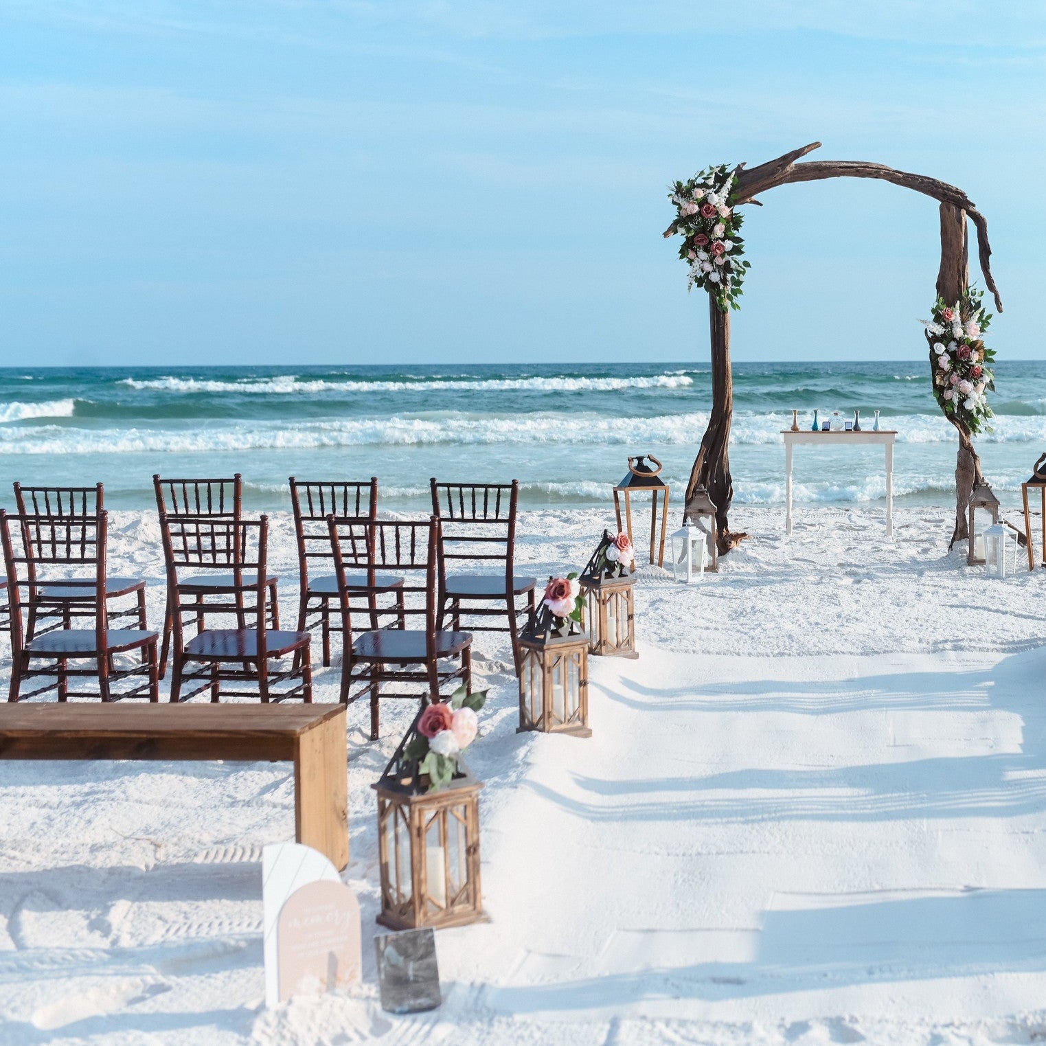 Mahogany chiavari chair rental in panama city beach for a beach wedding with the signature driftwood arbor and wedding flowers by the wedding shop