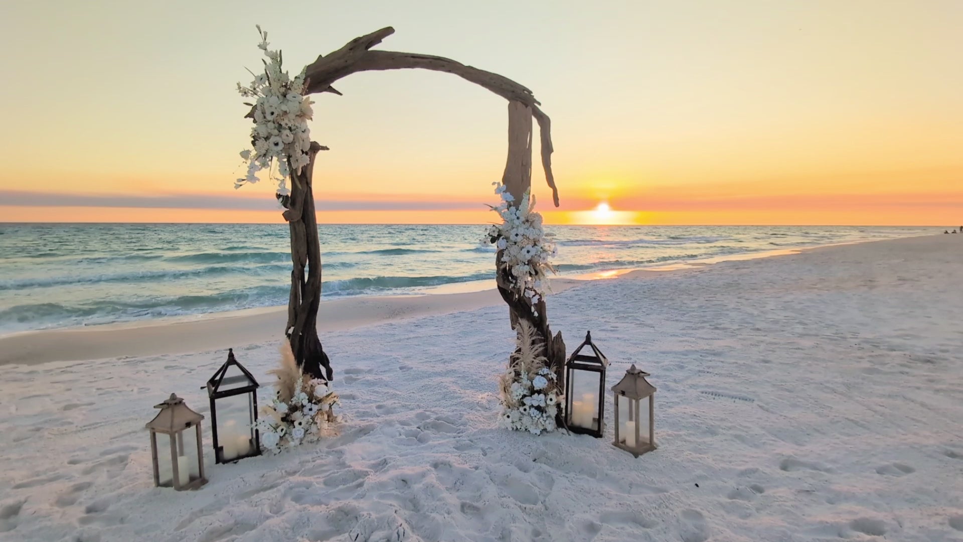 video of driftwood wedding arbor rental on the beach at sunset as waves crash behind it.
