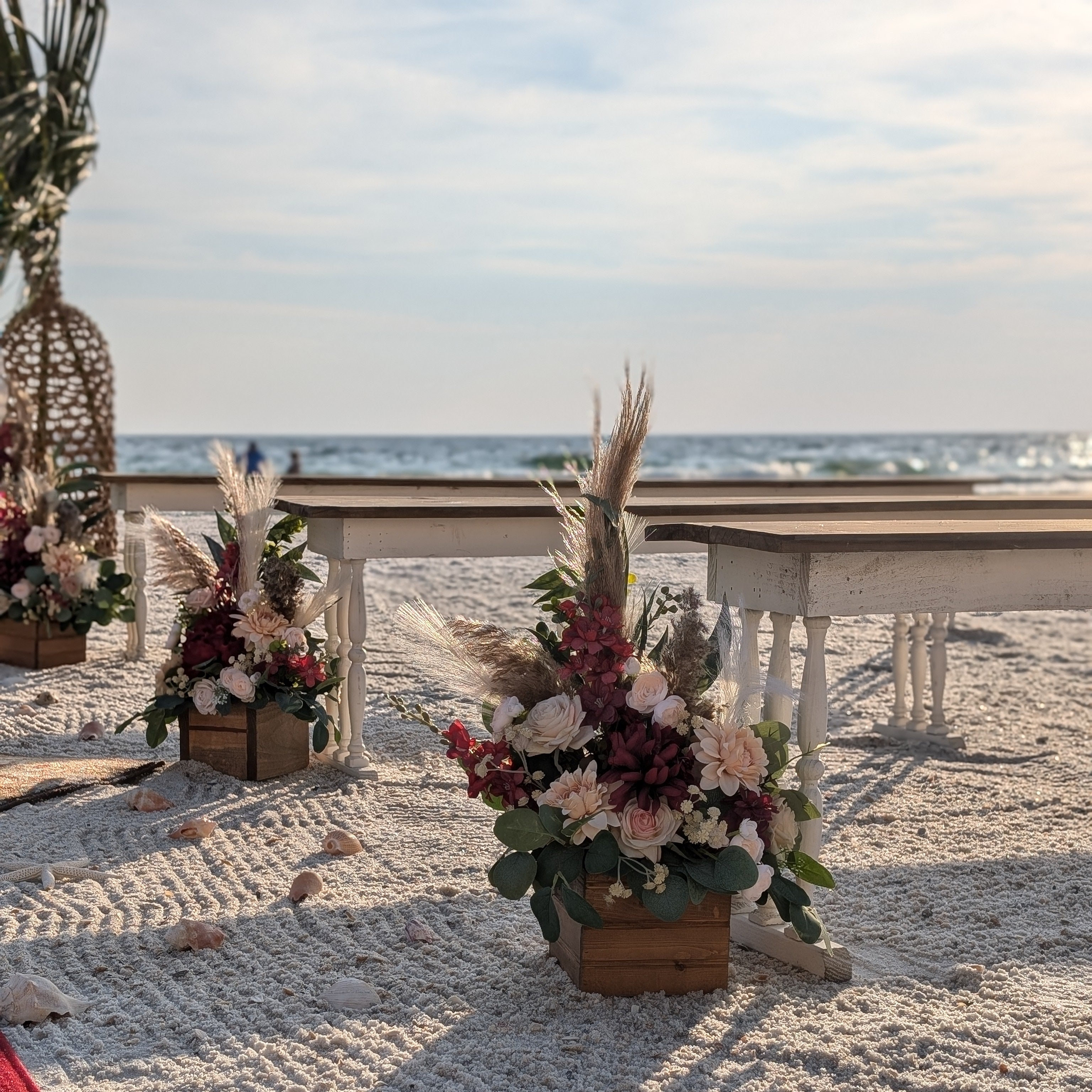 2-toned spindle leg bench seating rental for a beach wedding ceremony with flower box aisle markers and beachy boho flowers by the weddings shop for a beach wedding in panama city beach on the emerald coast