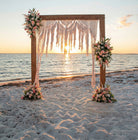 Decorative arch with macrame and flowers on a beach at sunset