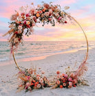 Gold Circle Floral arch on a beach with a sunset in the background