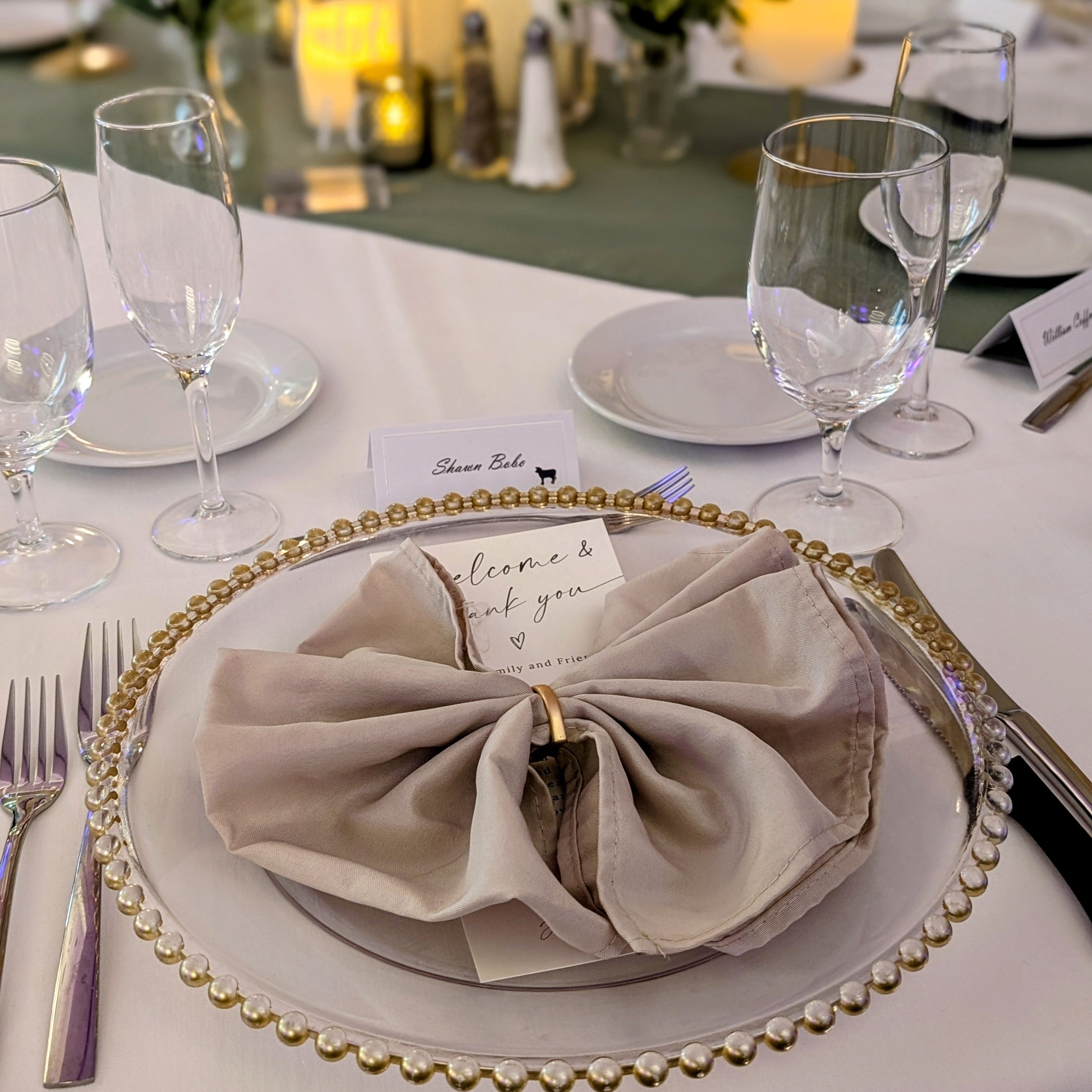 Elegant table setting with gold-rimmed plates, silverware, and a folded beige napkin rentals in panama city beach.