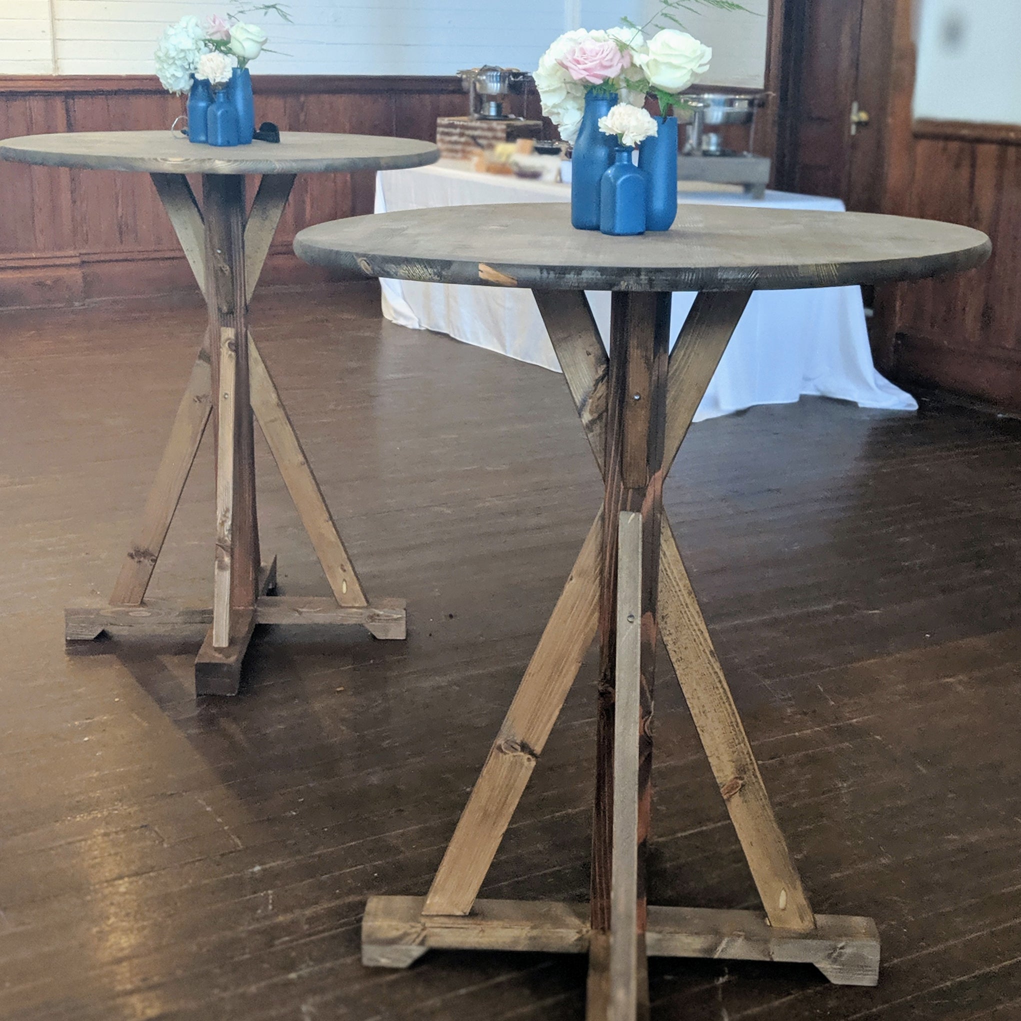 Tall cocktail table farmhouse style with large wooden table top and crisscross table legs rental for wedding party or event