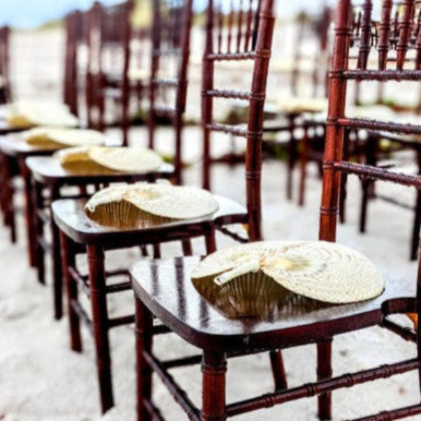 mahogany chiavari chair rental in panama city beach with fan favors for wedding ceremony guests.