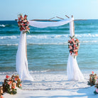Decorative branch wedding arch with flowers on a beach with ocean in the background