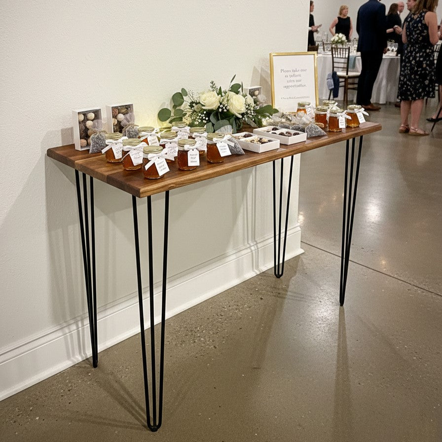 Wooden favors table with jars and flowers against a white wall at a wedding reception.