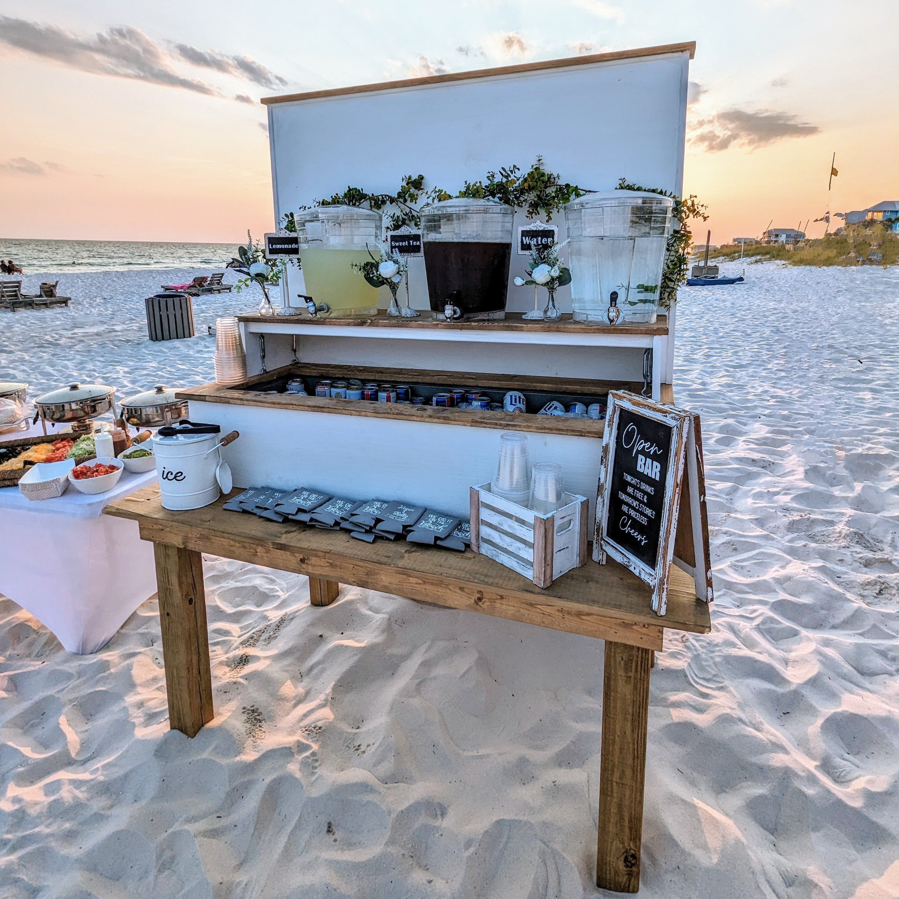 Beachside bar rental in panama city beach with drinks and snacks on a sandy beach at sunset.