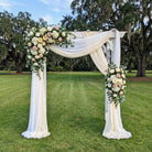 Decorative arch with floral arrangements on a grassy area