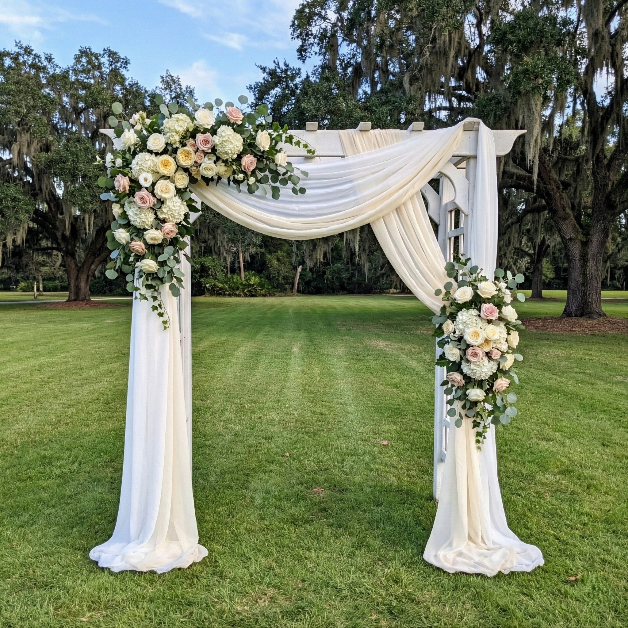 Decorative arch with floral arrangements on a grassy area
