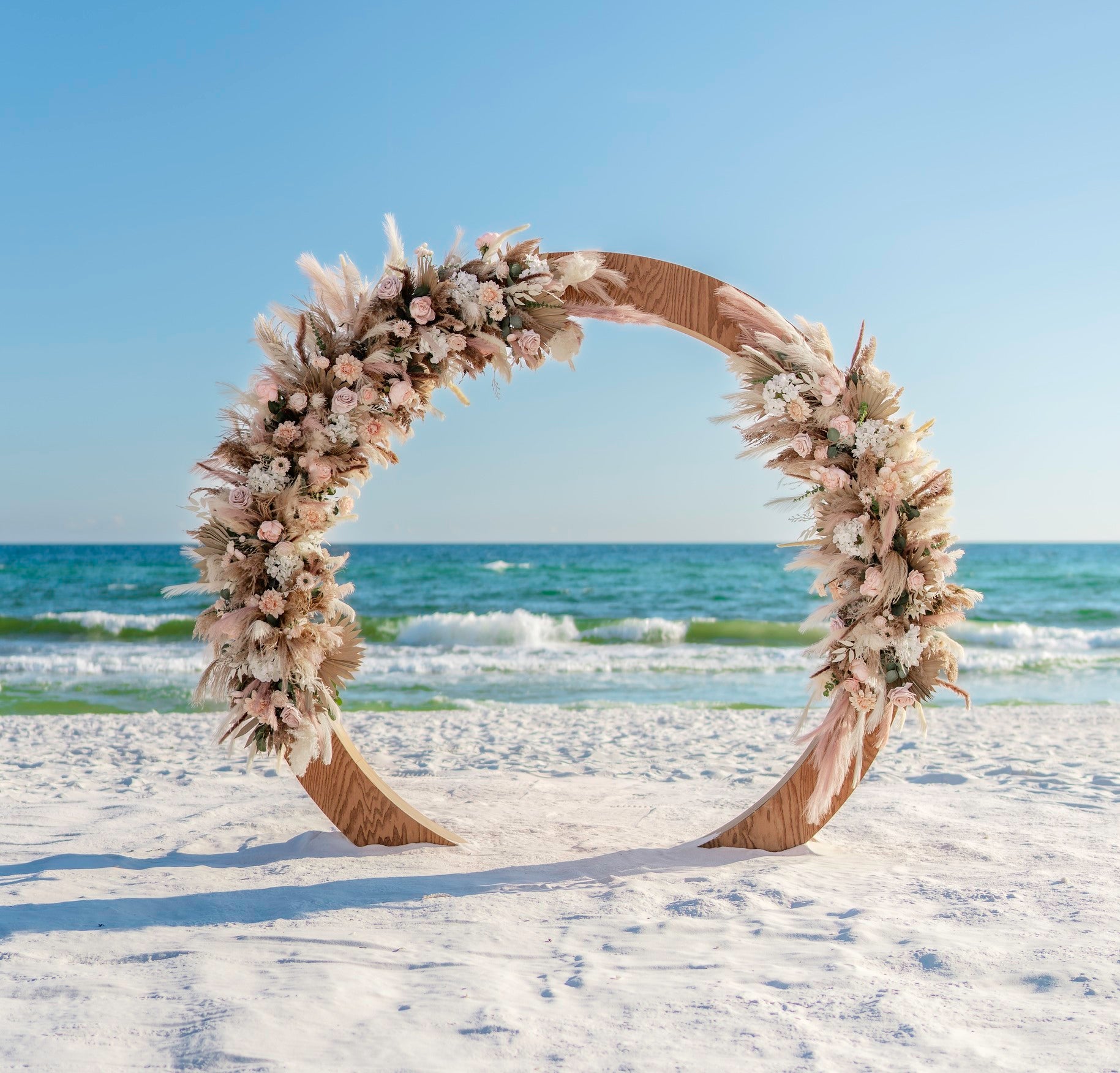 wood circle moon gate wedding arbor rental with boho flowers and pampas grass accents on the beach in panama city beach